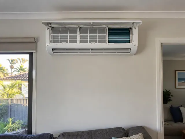 Clean split system with open front panel and visible filters on a white wall in a modern home in Broadbeach
