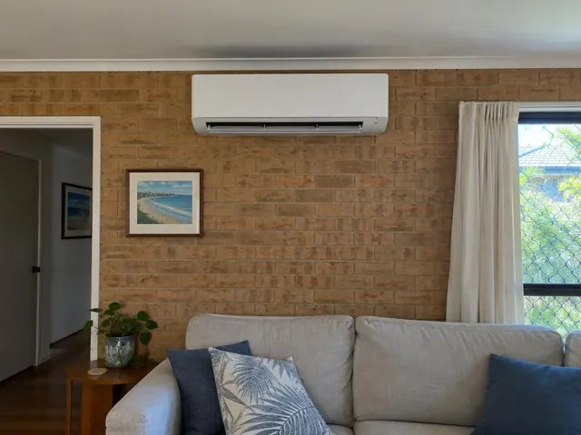 Split system indoor unit on a brick wall above a sofa in a living room in Mermaid Beach